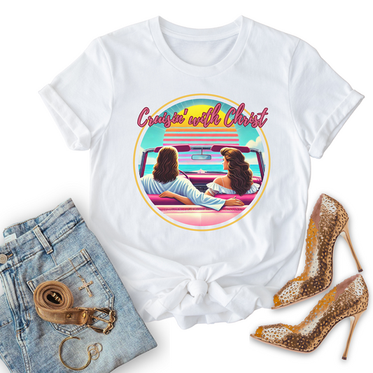 Cruisin' with Christ, white Christian T-shirts, graphic design of two people in a car, paired with jeans and high heels on a white background.